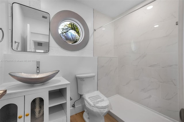 bathroom featuring a shower, toilet, wood finished floors, and vanity