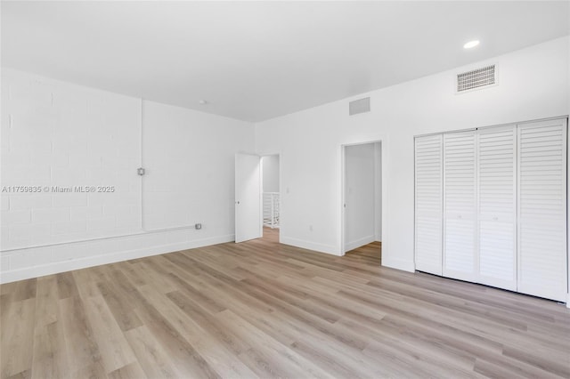 unfurnished bedroom with visible vents, baseboards, light wood-style floors, and a closet