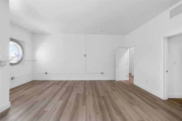 empty room featuring wood finished floors, visible vents, and baseboards