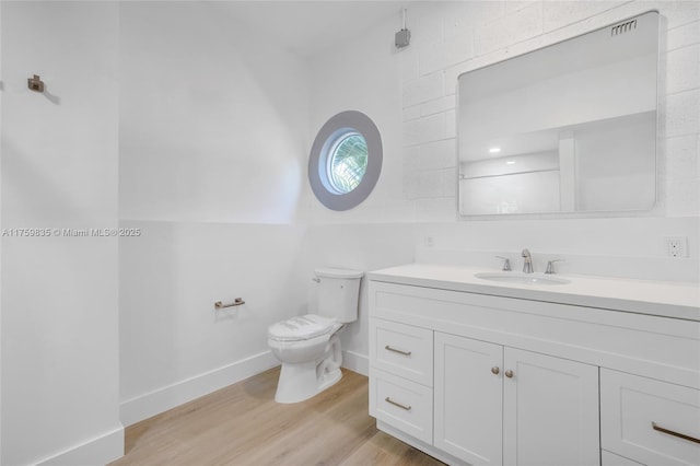 bathroom with vanity, toilet, wood finished floors, and baseboards