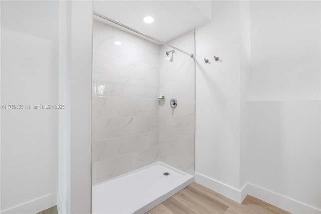 bathroom featuring a shower stall, baseboards, and wood finished floors