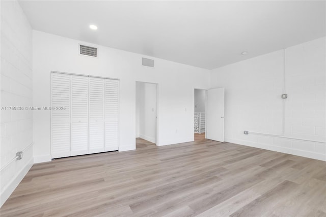 unfurnished bedroom featuring wood finished floors, visible vents, and a closet