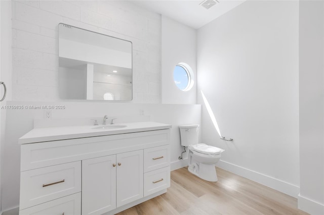 bathroom with visible vents, baseboards, toilet, wood finished floors, and vanity