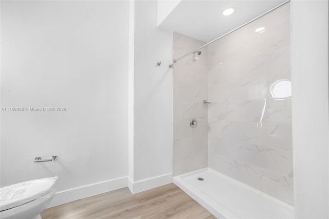 bathroom featuring a walk in shower, toilet, baseboards, and wood finished floors