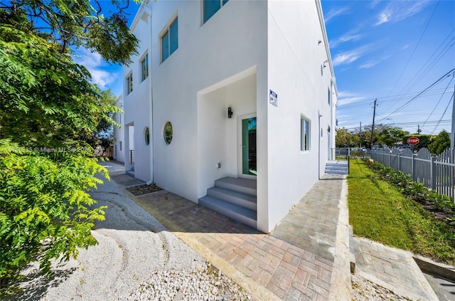 exterior space featuring entry steps, fence, and stucco siding