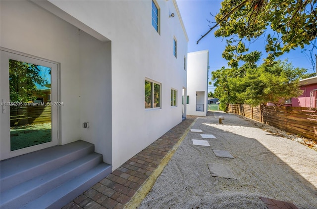 view of home's exterior with a patio area, stucco siding, and fence