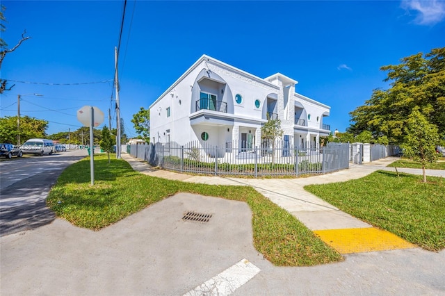 view of front facade with a fenced front yard, a balcony, a front yard, and stucco siding