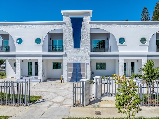 view of front of home with a gate, driveway, an attached garage, stucco siding, and a fenced front yard