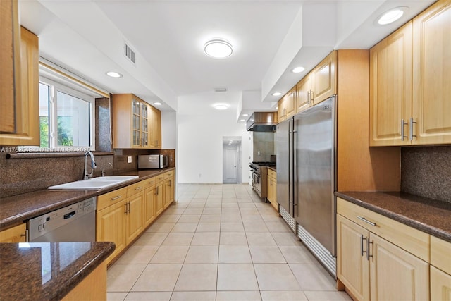 1690 Daytonia Rd, Miami Beach, FL 33141 - kitchen with high end appliances, a sink, light tile patterned floors, tasteful backsplash, and glass insert cabinets