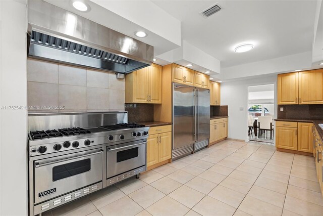 1690 Daytonia Rd, Miami Beach, FL 33141 - kitchen with high end appliances, premium range hood, light tile patterned flooring, dark countertops, and recessed lighting