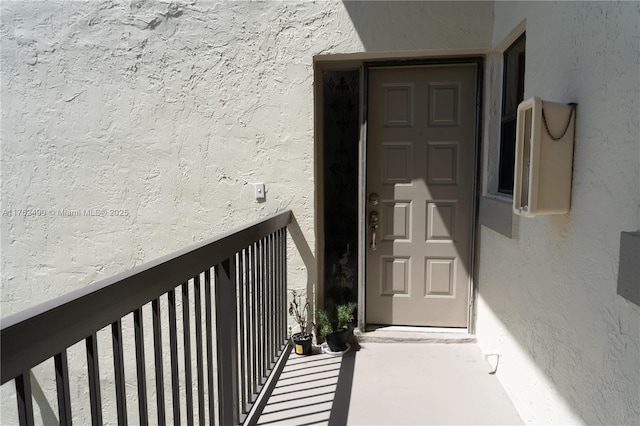 property entrance with stucco siding and a balcony