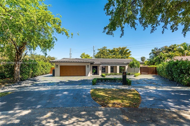 ranch-style house with concrete driveway, a tiled roof, an attached garage, and stucco siding