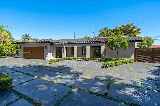 view of front facade with stucco siding, driveway, an attached garage, and a tiled roof