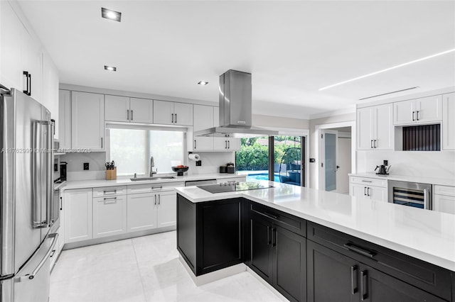 kitchen with island exhaust hood, freestanding refrigerator, a sink, light countertops, and wine cooler