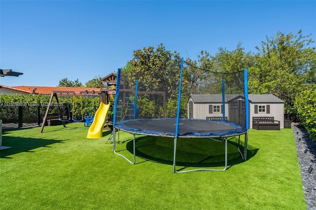 view of yard with fence, playground community, a shed, an outdoor structure, and a trampoline