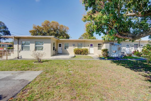 rear view of property featuring a yard, fence, and stucco siding