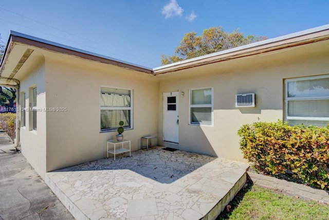 property entrance featuring stucco siding, a patio, and a wall mounted AC