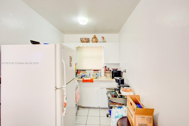 kitchen with white cabinetry, light countertops, light tile patterned flooring, and freestanding refrigerator