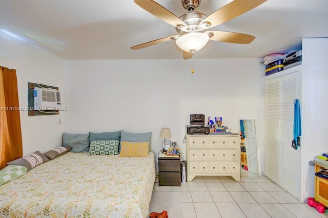 bedroom with a wall unit AC, light tile patterned flooring, a closet, and ceiling fan