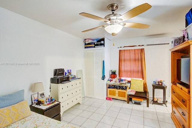 bedroom with light tile patterned flooring, an AC wall unit, a closet, and a ceiling fan