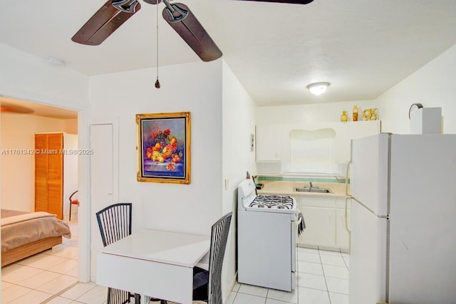 kitchen featuring ceiling fan, light tile patterned floors, white appliances, white cabinetry, and a sink