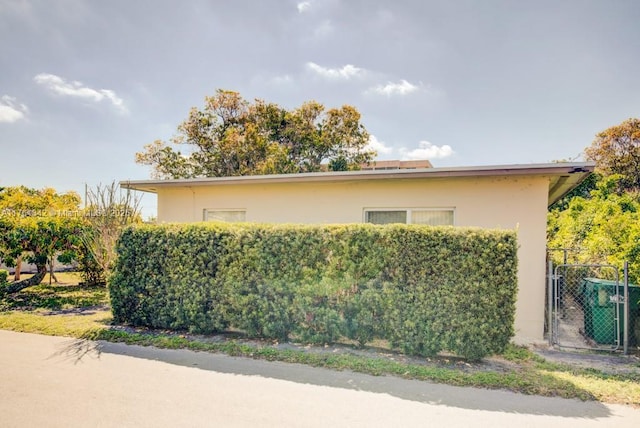 view of side of home featuring stucco siding and a gate