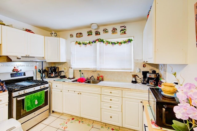 kitchen with range hood, gas stove, a sink, light countertops, and white cabinets