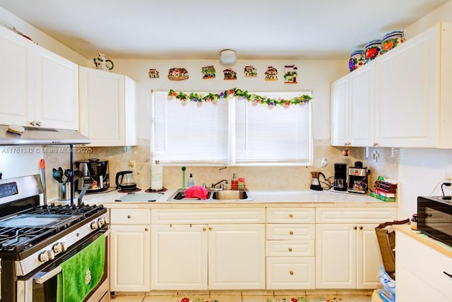 kitchen with under cabinet range hood, backsplash, stainless steel range with gas cooktop, and a sink