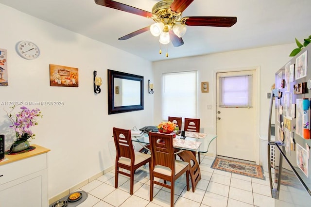 dining space featuring light tile patterned floors, baseboards, and a ceiling fan