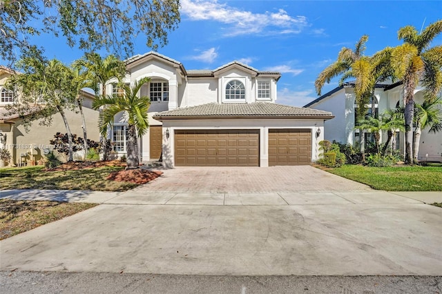 mediterranean / spanish-style home featuring a tiled roof, stucco siding, driveway, and an attached garage