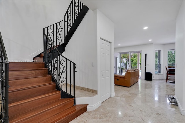 stairway featuring recessed lighting, marble finish floor, and baseboards