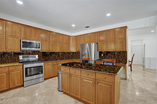 kitchen featuring backsplash, dark stone counters, a kitchen island, and appliances with stainless steel finishes