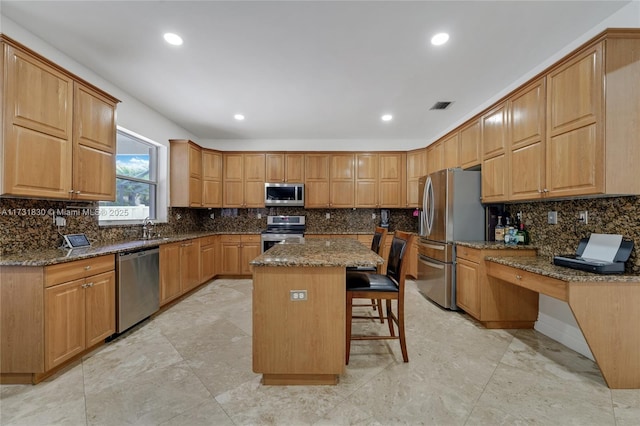 kitchen with visible vents, a breakfast bar, dark stone counters, appliances with stainless steel finishes, and a center island