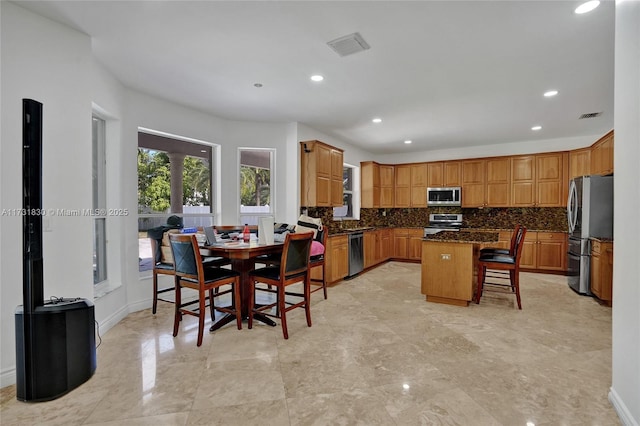 kitchen featuring a center island, decorative backsplash, appliances with stainless steel finishes, and a breakfast bar area