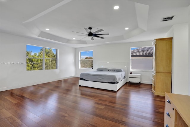 bedroom featuring visible vents, recessed lighting, a tray ceiling, and dark wood-style flooring