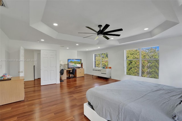 bedroom featuring a tray ceiling, recessed lighting, and wood finished floors