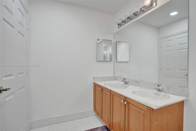 full bath with tile patterned floors, double vanity, baseboards, and a sink