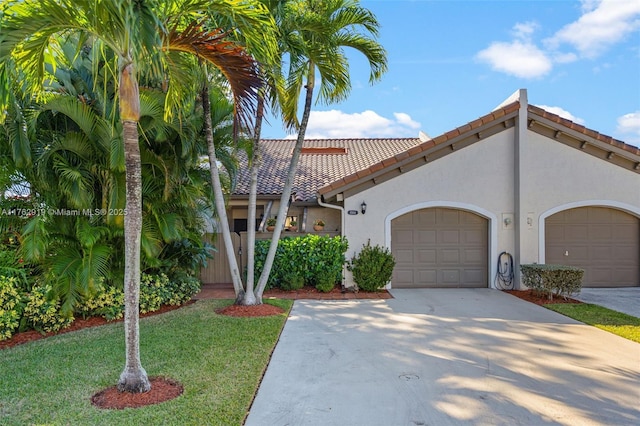 mediterranean / spanish-style house featuring stucco siding, a front lawn, driveway, a tile roof, and an attached garage