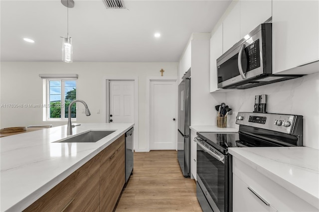 kitchen featuring visible vents, a sink, decorative light fixtures, appliances with stainless steel finishes, and white cabinets