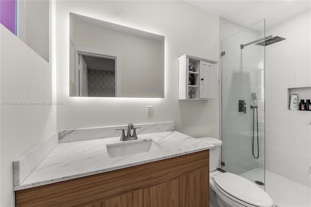 bathroom with vanity, toilet, and a tile shower