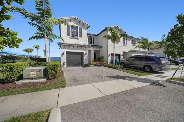 view of front facade with decorative driveway, a garage, and stucco siding