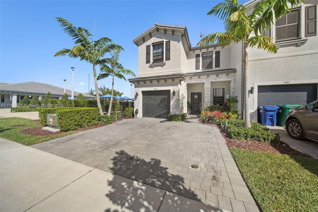 view of front of property with decorative driveway, an attached garage, and stucco siding