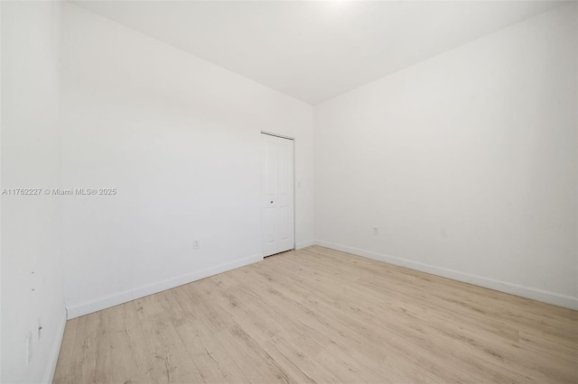 spare room with baseboards and light wood-style flooring