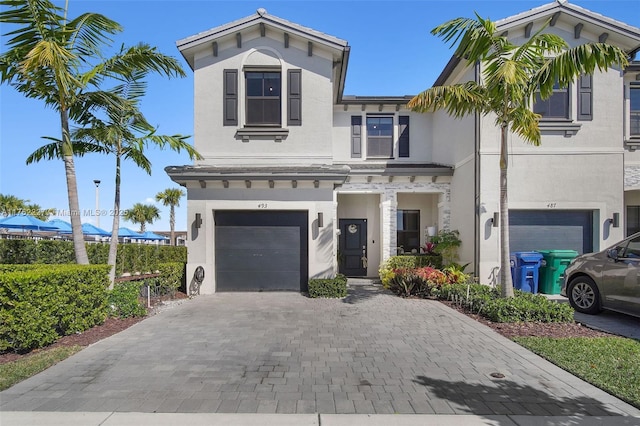 view of front facade featuring stucco siding, decorative driveway, and an attached garage