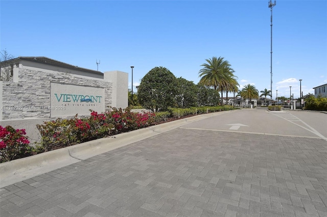 view of street featuring a gated entry, curbs, and street lights