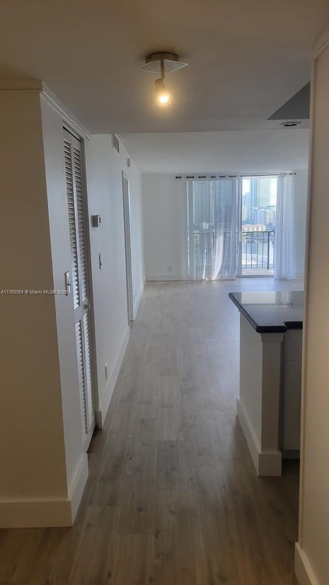 corridor featuring wood finished floors, visible vents, and baseboards