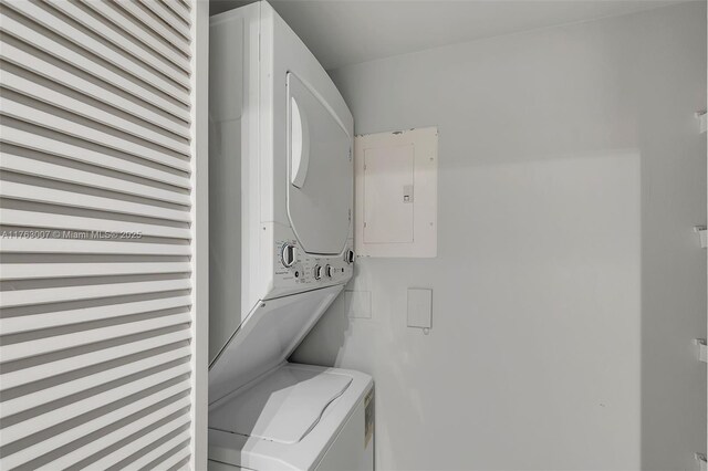 laundry room with electric panel and stacked washing maching and dryer