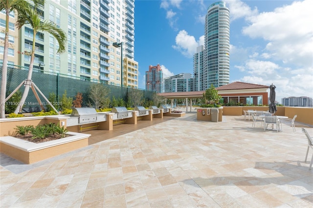 view of patio featuring area for grilling, an outdoor kitchen, a view of city, and fence