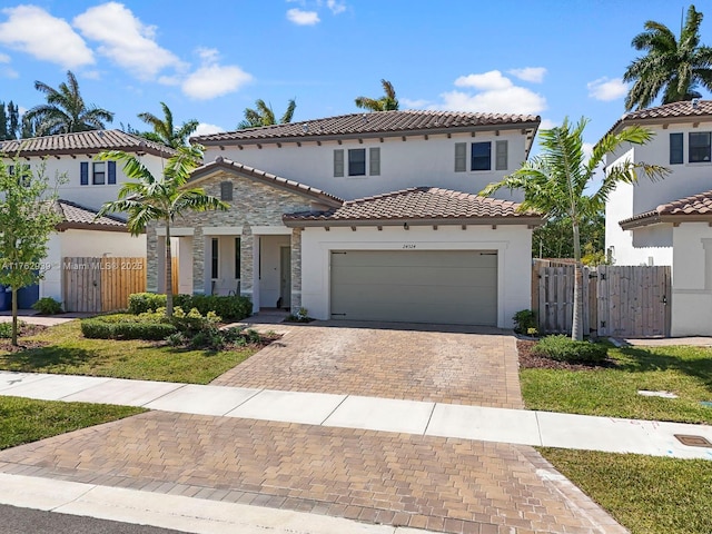 mediterranean / spanish home featuring a garage, decorative driveway, fence, and a gate