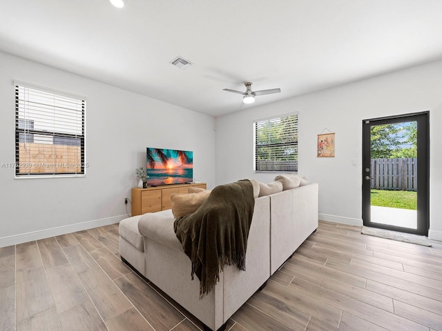 living room featuring visible vents, ceiling fan, light wood-type flooring, and baseboards